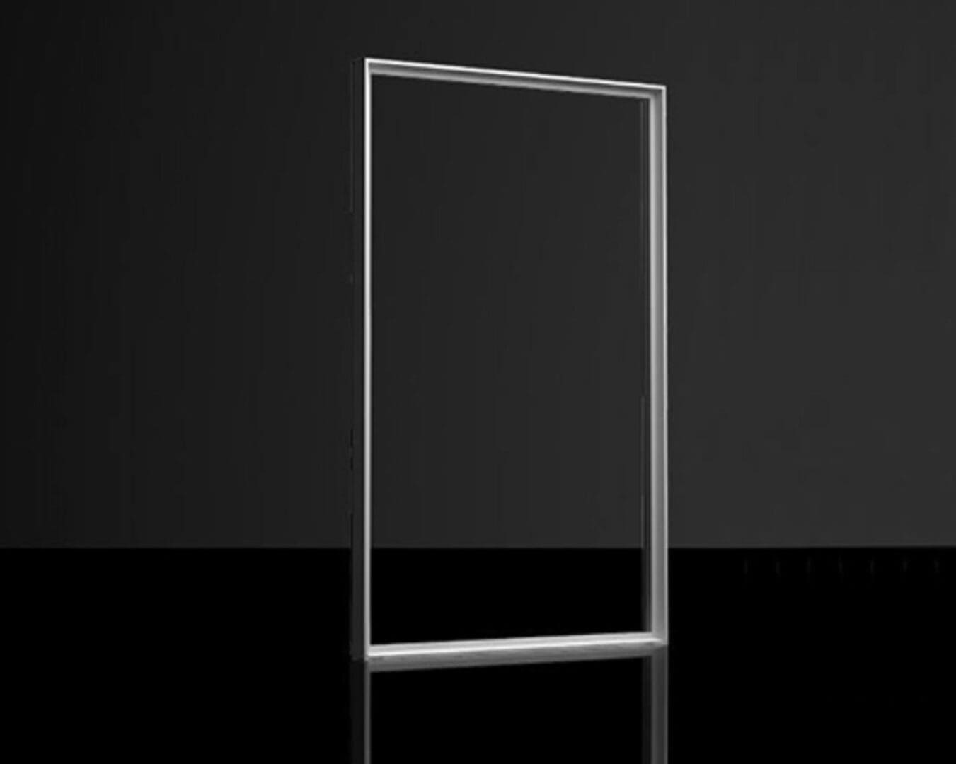 A glass frame on the floor in front of a black wall.